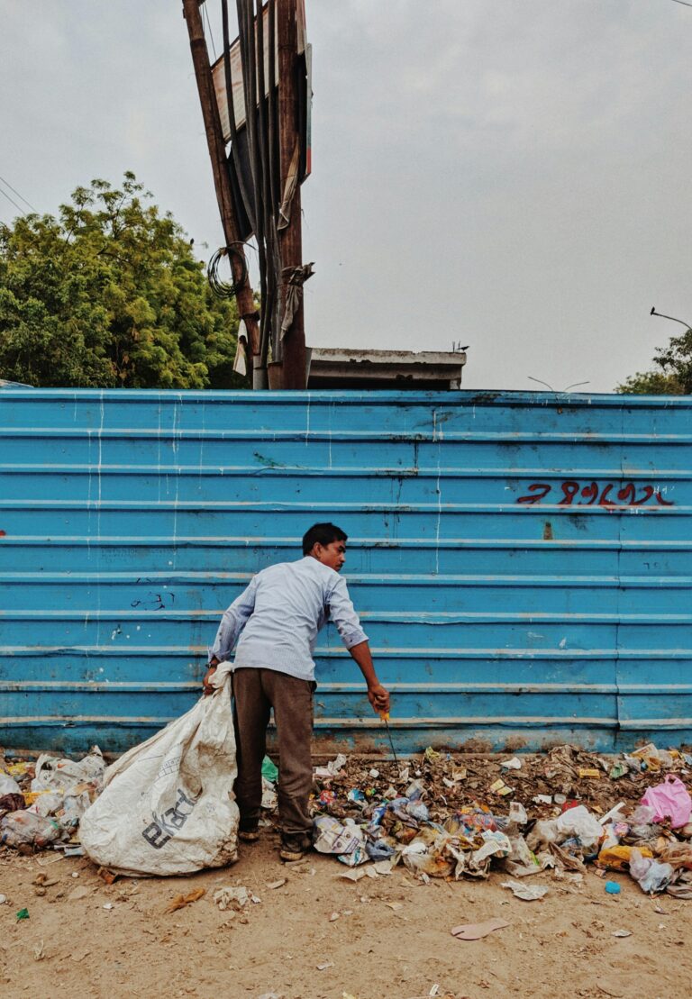 A man collects trash in a vibrant urban setting, highlighting waste management in Noida, India.