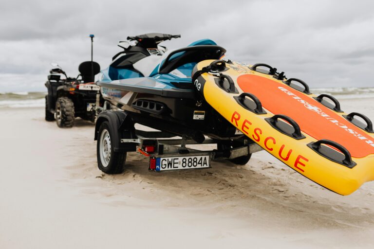 Jet ski and rescue float ready for emergency on a sandy beach under cloudy skies.