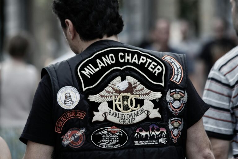 Close-up of a biker wearing a Milano Chapter Harley Owners Group vest adorned with patches.