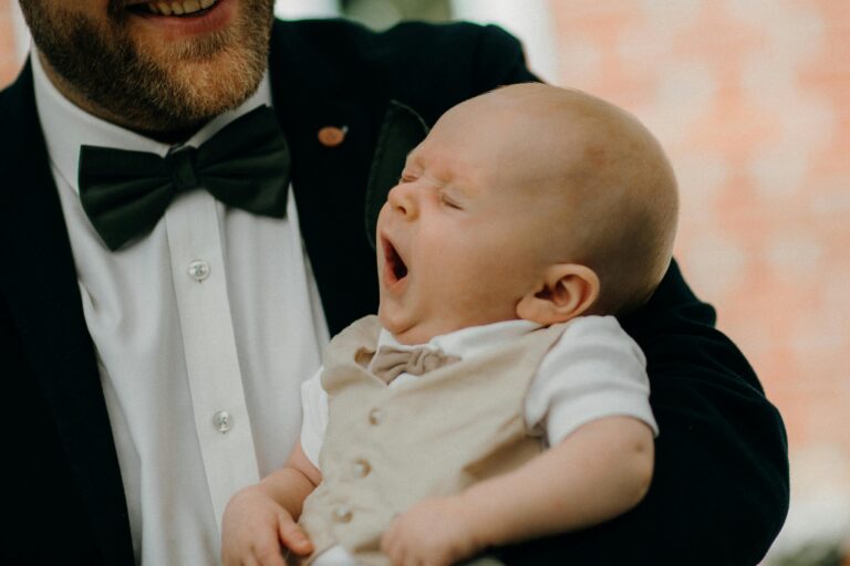 Capture of a cute baby yawning in formal attire, exuding innocence and charm.