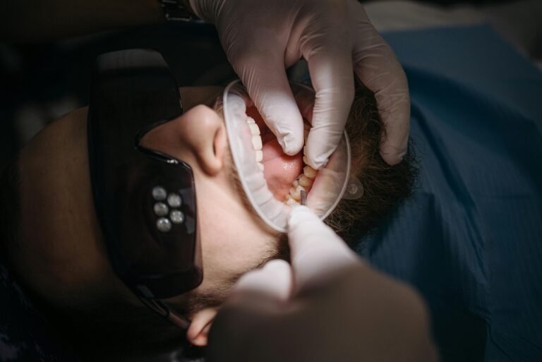 A dentist's hands examining a patient's teeth using specialized tools.