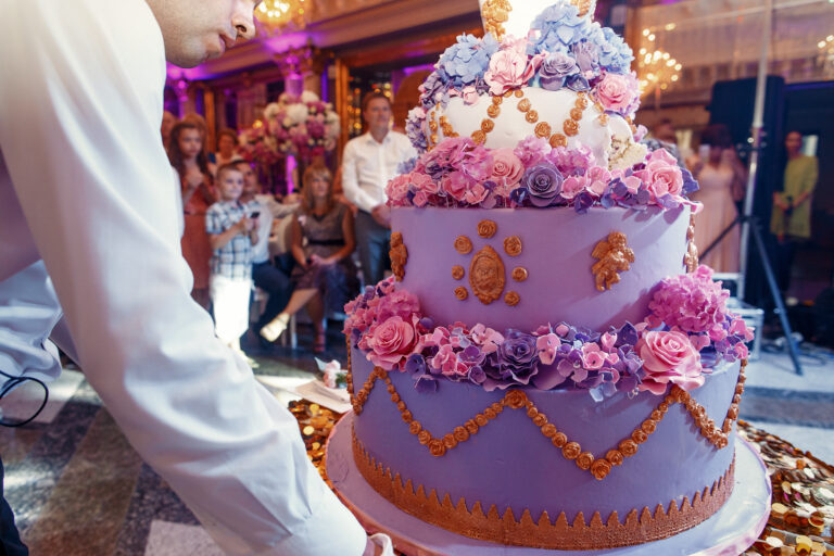 Waiter carries luxurious  violet wedding cake decorated with flo
